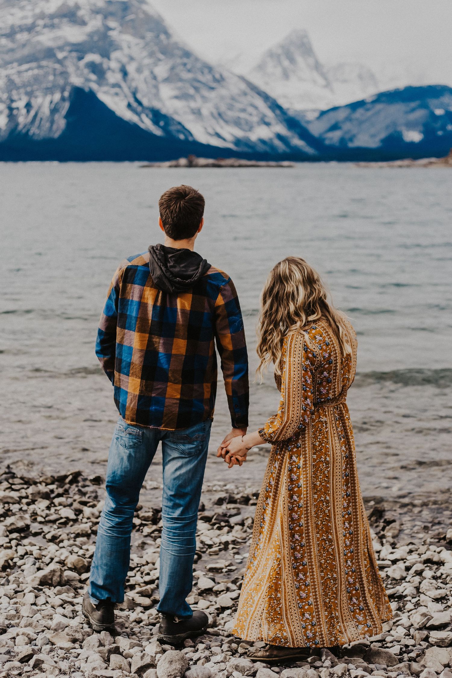 couple hold hands while looking at the kananaskis mountains
