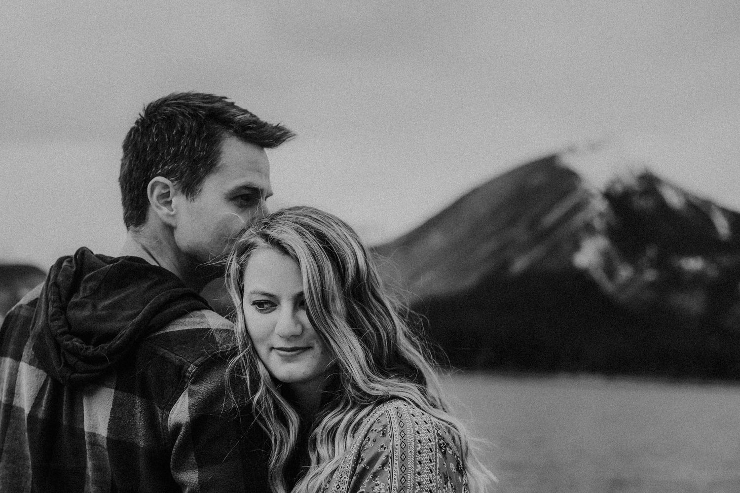 man kisses wife on head in front of mountains
