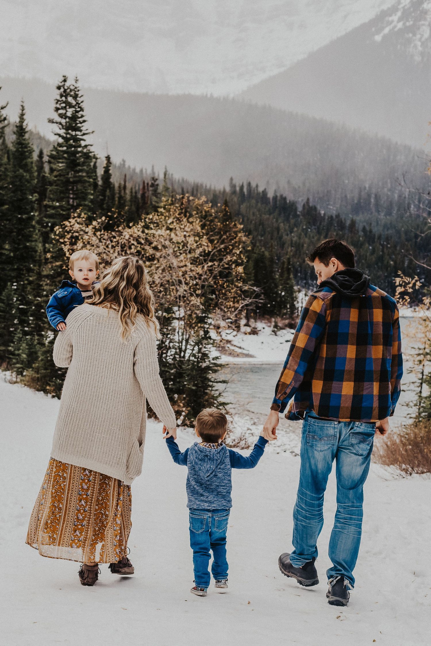 family of four walks hand in hand in front of mountains
