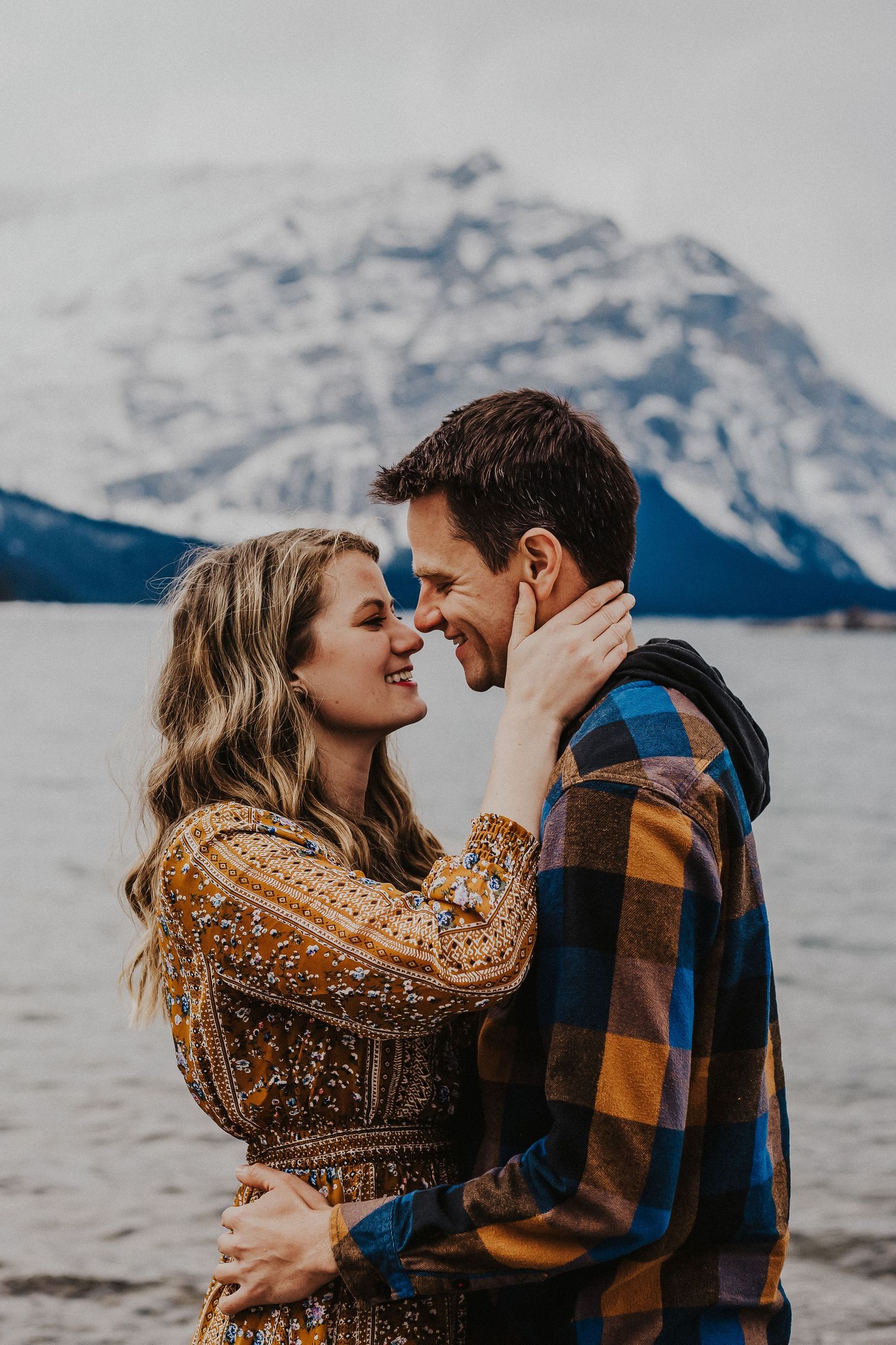 couple touch noses while smiling in front of upper kananaskis lake