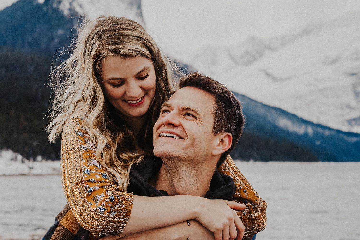 man and woman laugh as he gives her a piggyback