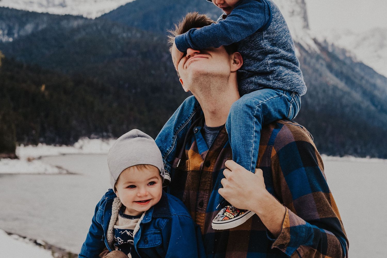 son on dad's shoulders covers his dad's eyes