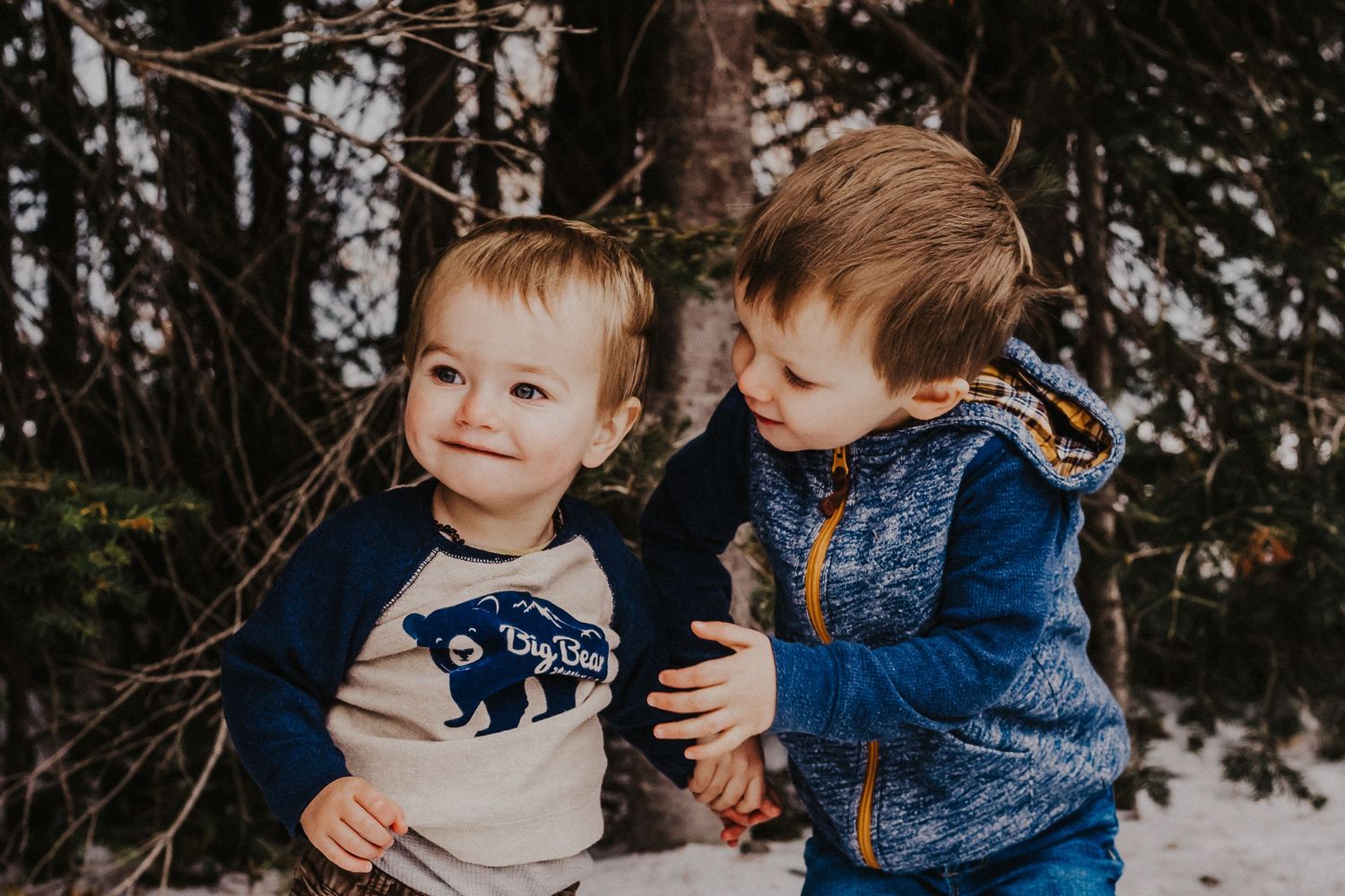 big brother lovingly holds younger brother in the forest