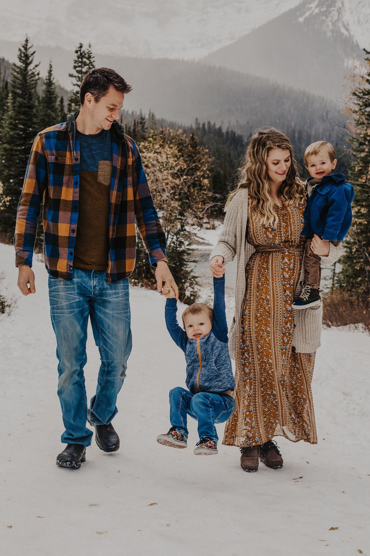 Parents swing and carry boys in front of mountains