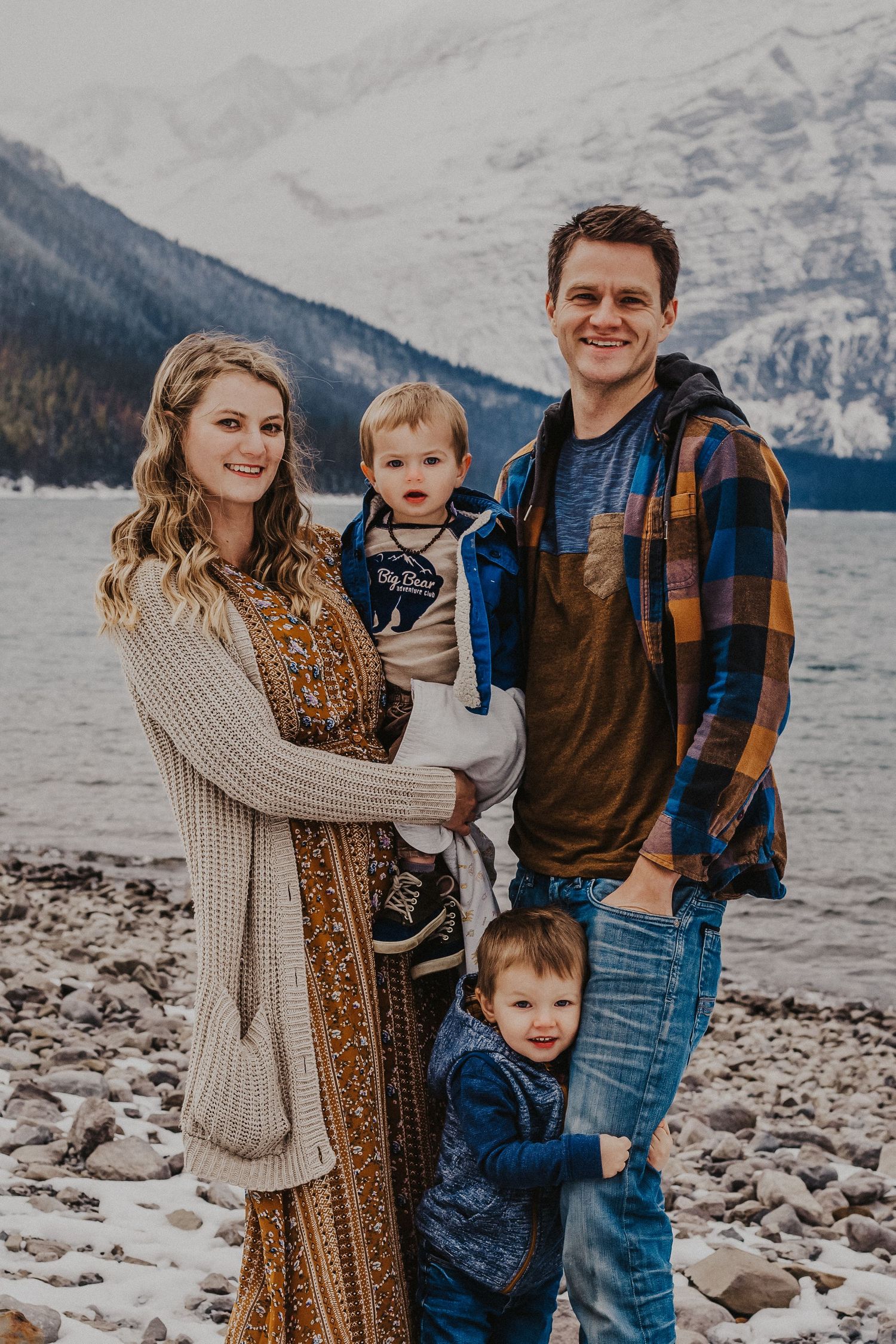 Mom and dad and two sons smile in front of moutains