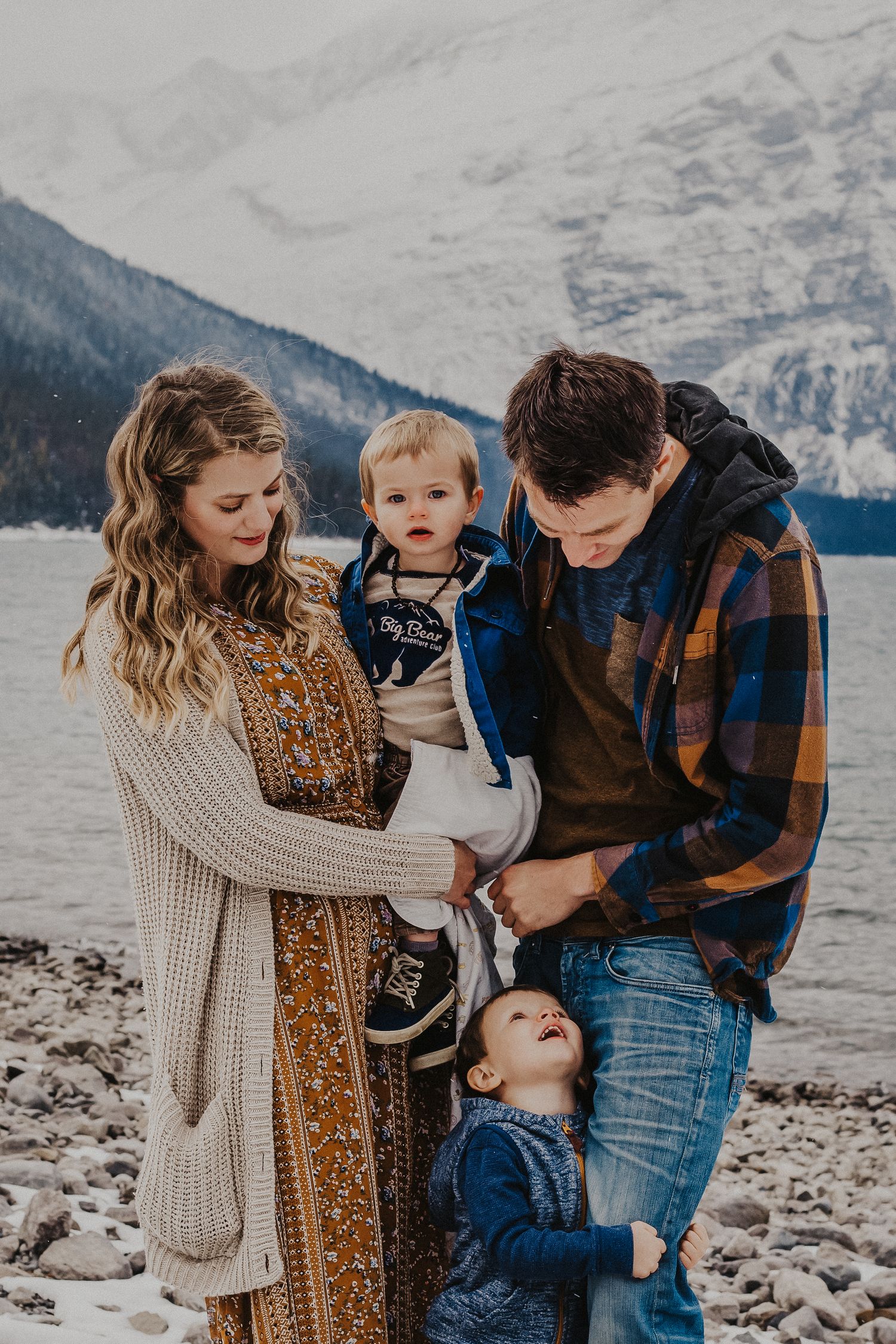 family of four stands in front of mountains smiling