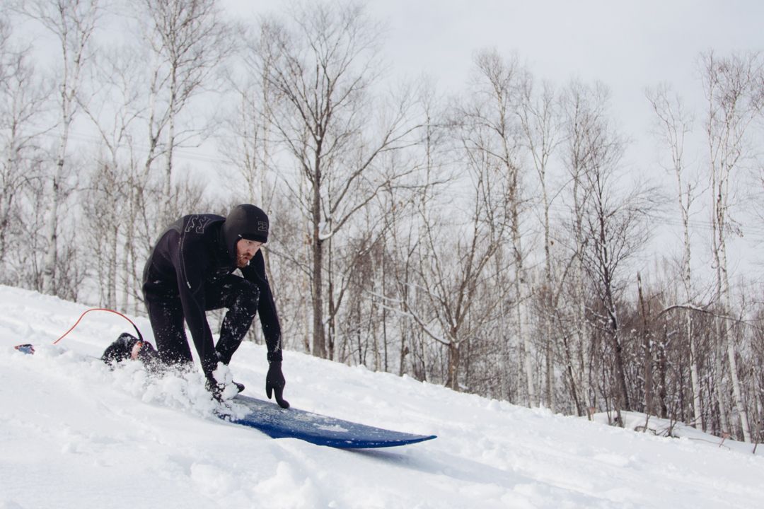 Action photo of popping up on a surf board whilst snowboarding down a mountain