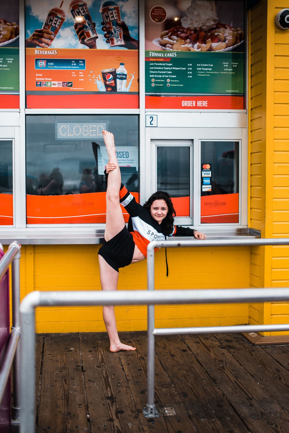Girl dancing/doing the splits in front of a food booth at Santa Monica Pier