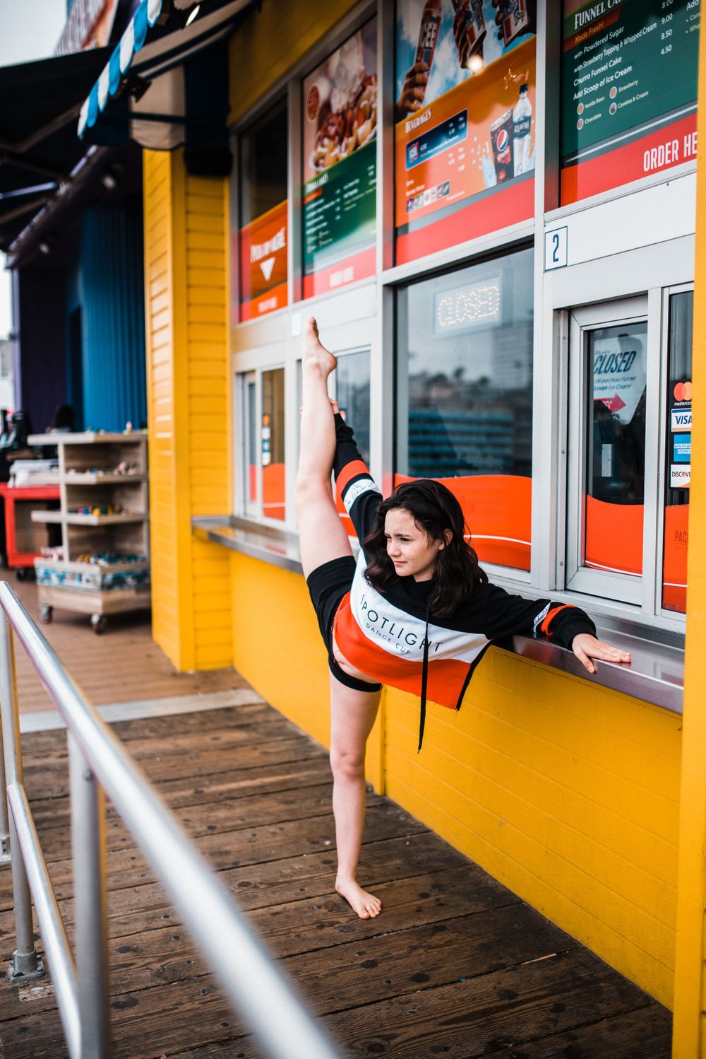 Girl dancing/doing the splits in front of a food booth at Santa Monica Pier