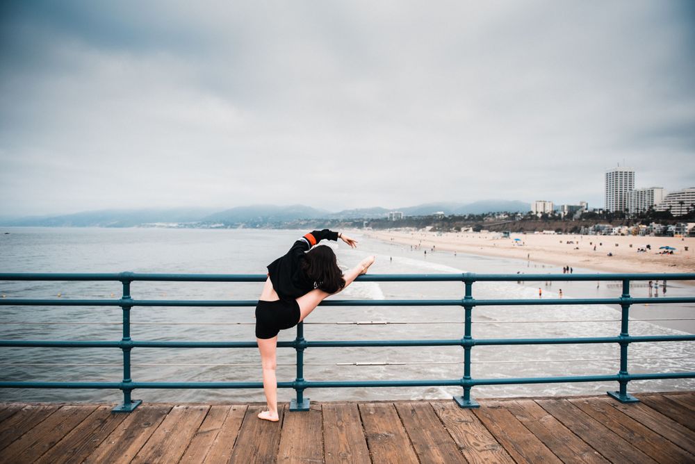 Girl stretching on the railing while overlooking the ocean and beach at Santa Monica Pier