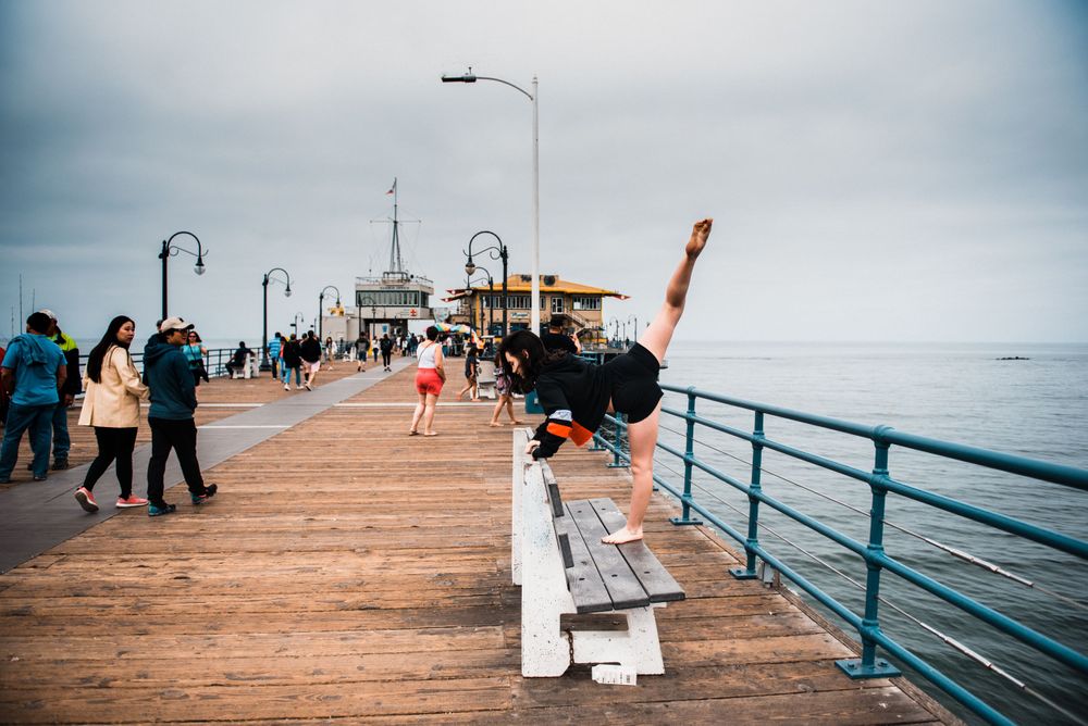 Girl dancing on a bench at Santa Monica Pier while strangers watch