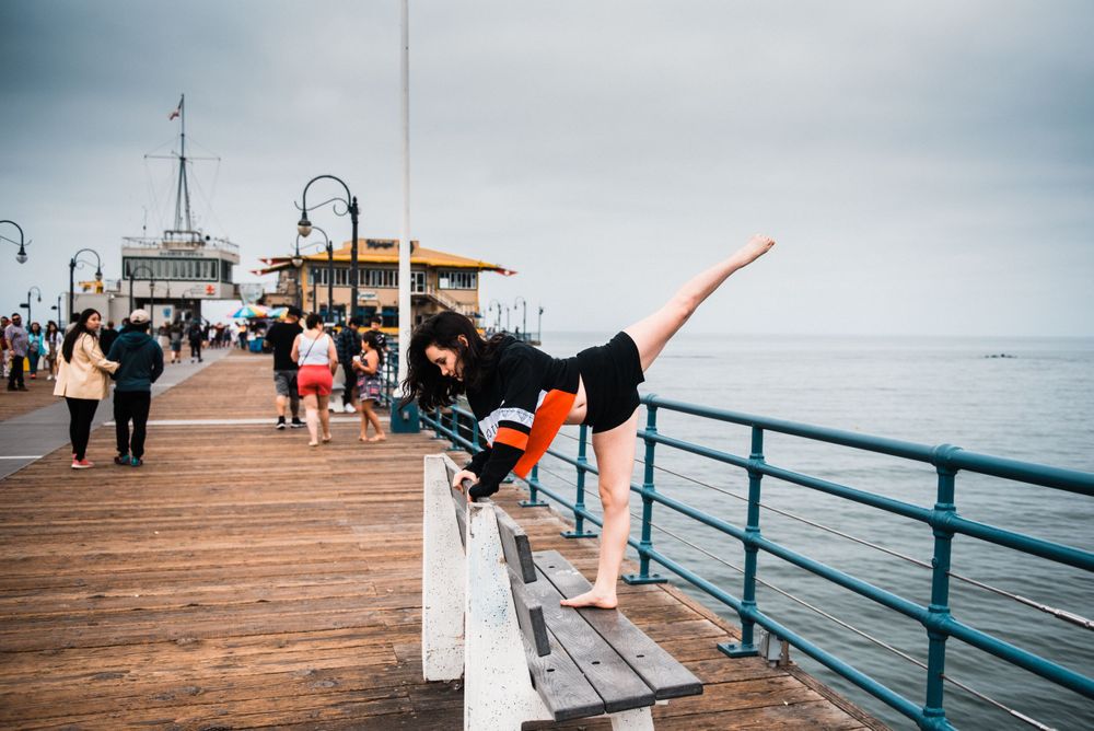 Girl dancing on a bench at Santa Monica Pier while strangers watch