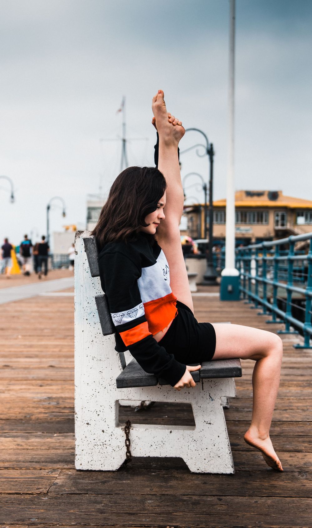Girl holding her leg up while dancing at Santa Monica Pier for a photoshoot