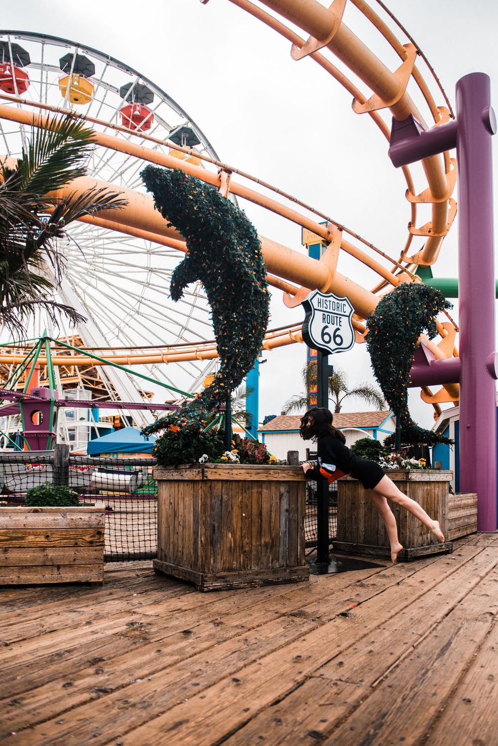 Girl dancing in front of a rollercoaster during a Santa Monica Pier photoshoot