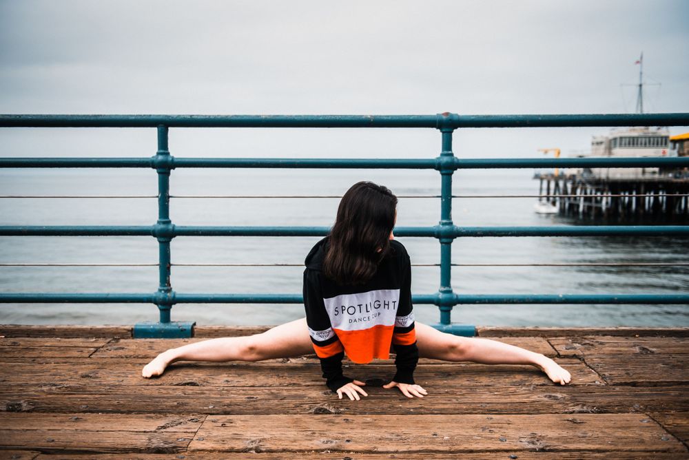 Girl doing the splits while dancing for a photoshoot at Santa Monica Pier