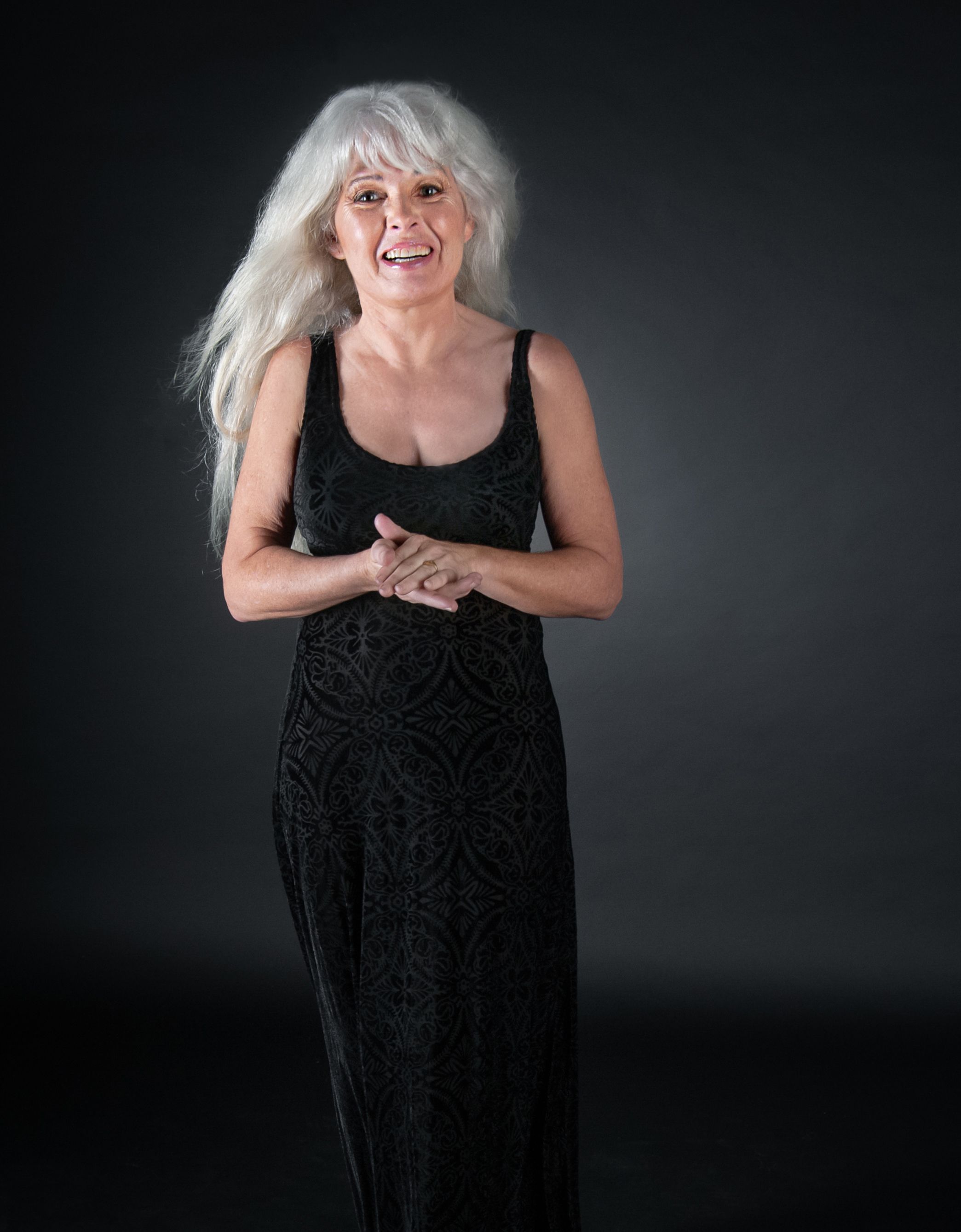 senior citizen with long silver hair stands for portrait