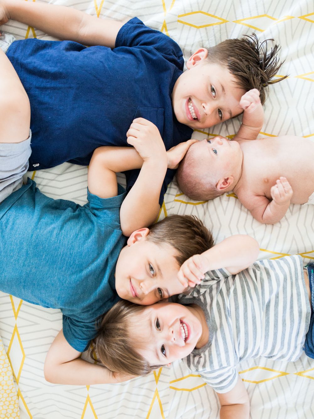 4 brothers on the bed with thier newest addition Maryland Newborn Photographer | DANIE Photography