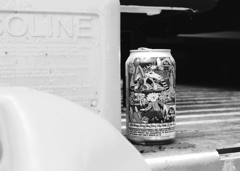 A beer can of PBR sitting next to a gas can on the back of a truck.