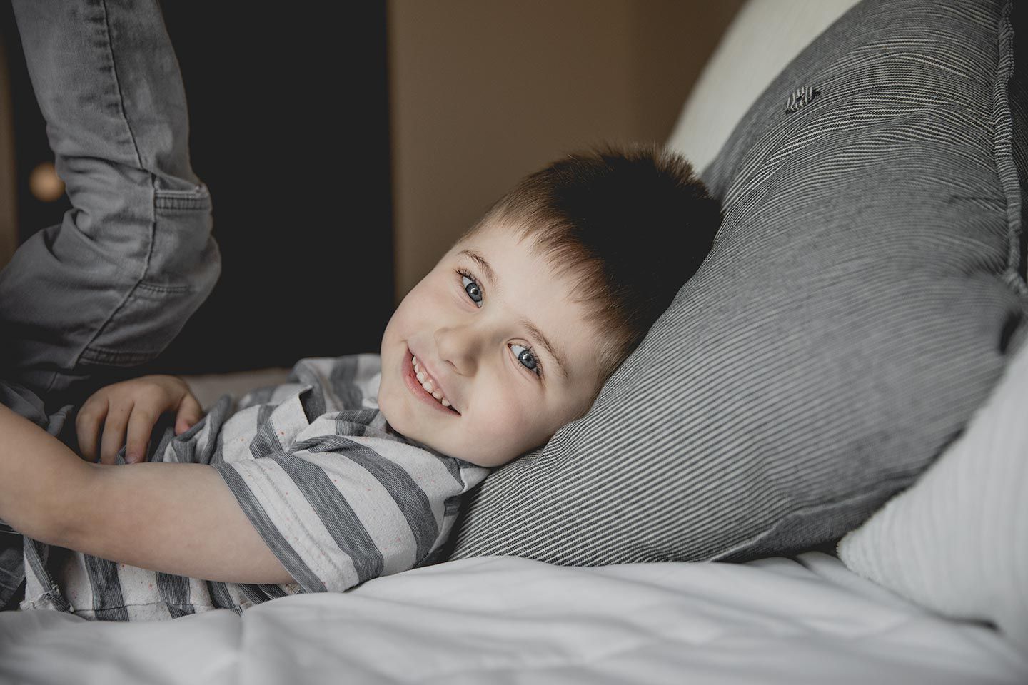 little boy laying on bed smiling
