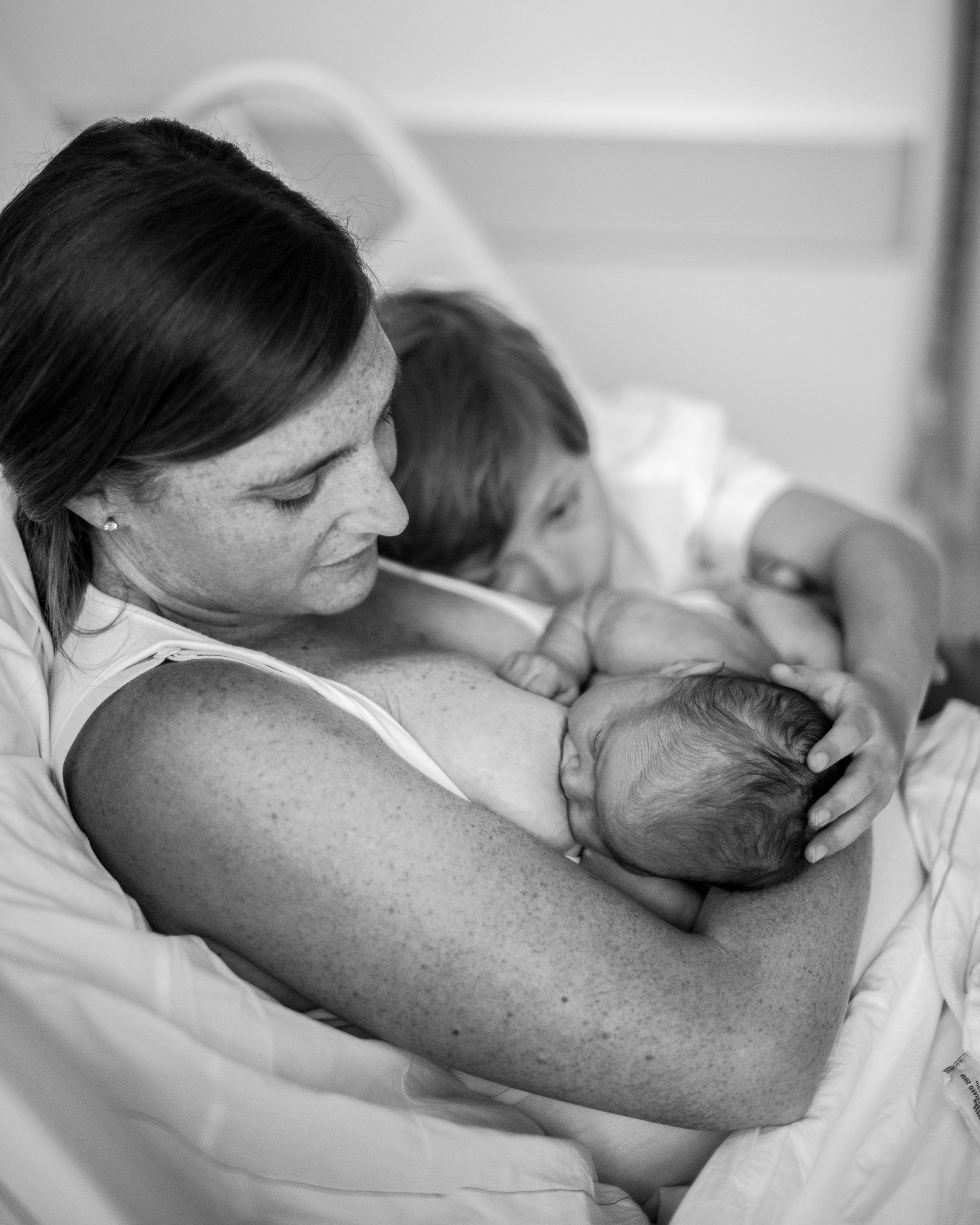Plymouth MA newborn photographer, Heidi Harting captures new mother nursing her infant as big brother looks on.