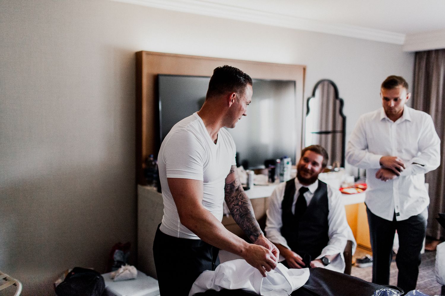 groom putting on white button up preparation for wedding day