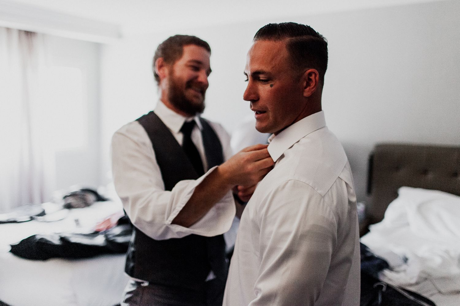 best man helping groom with button