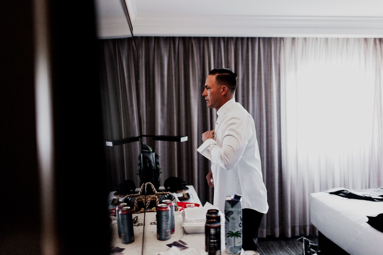 groom adjusting shirt in front of mirror