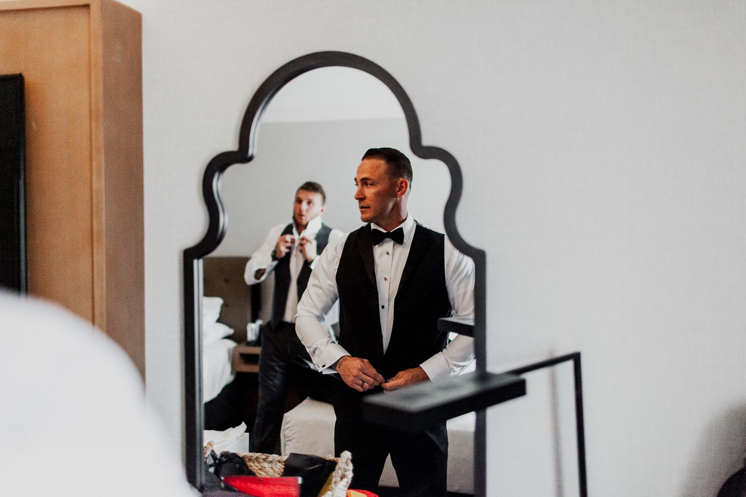 groom adjusting vest in mirror