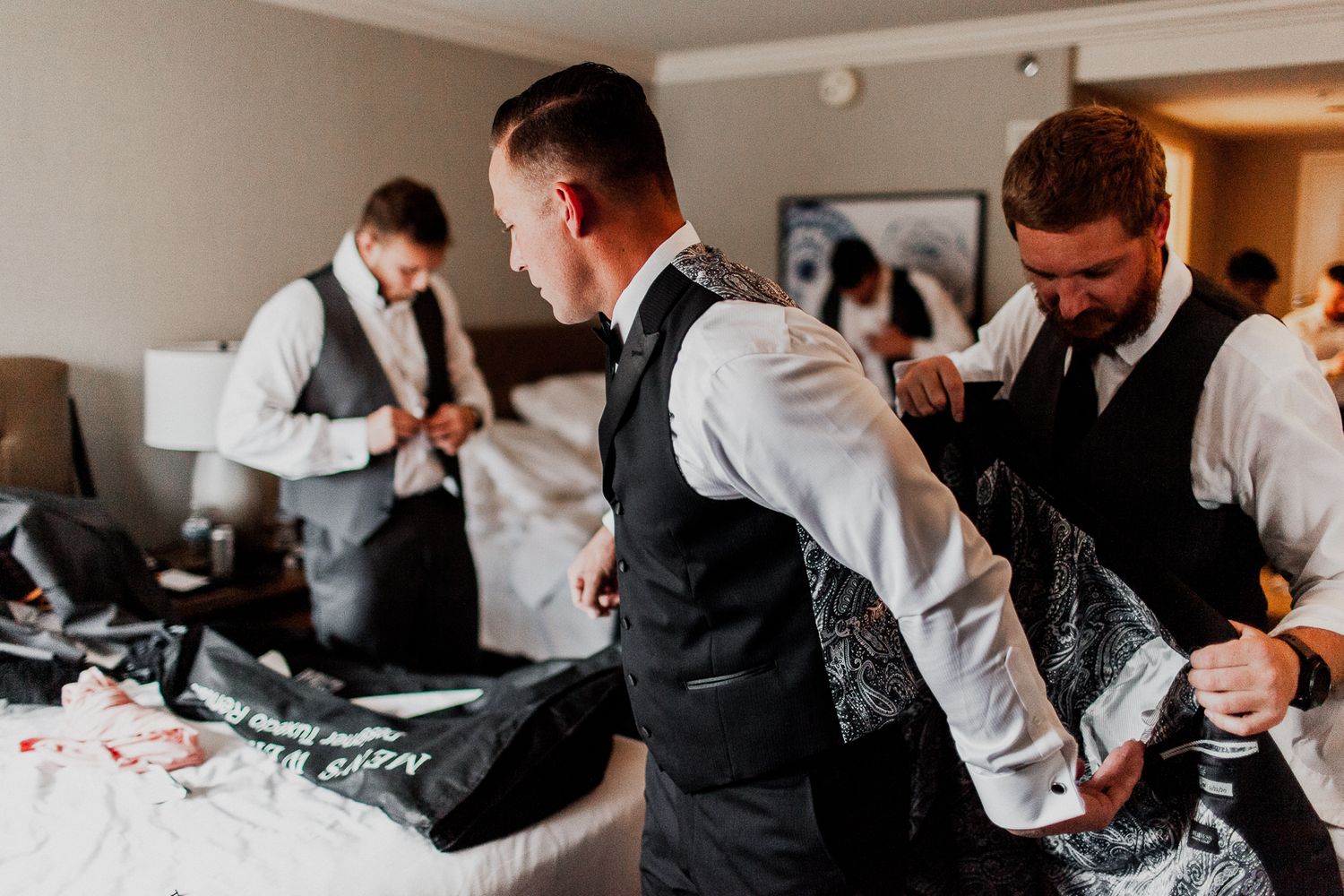 best man helping groom put on jacket
