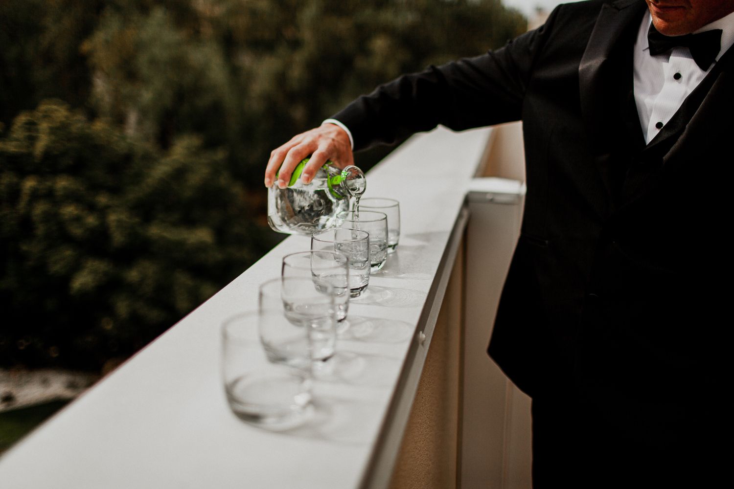 groom pouring patron drink in glasses for groomsmen
