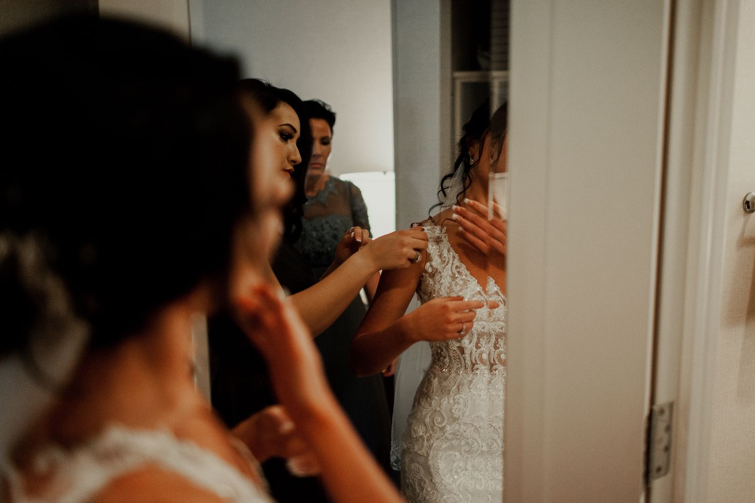 bride getting her dress adjusted by bridesmaid