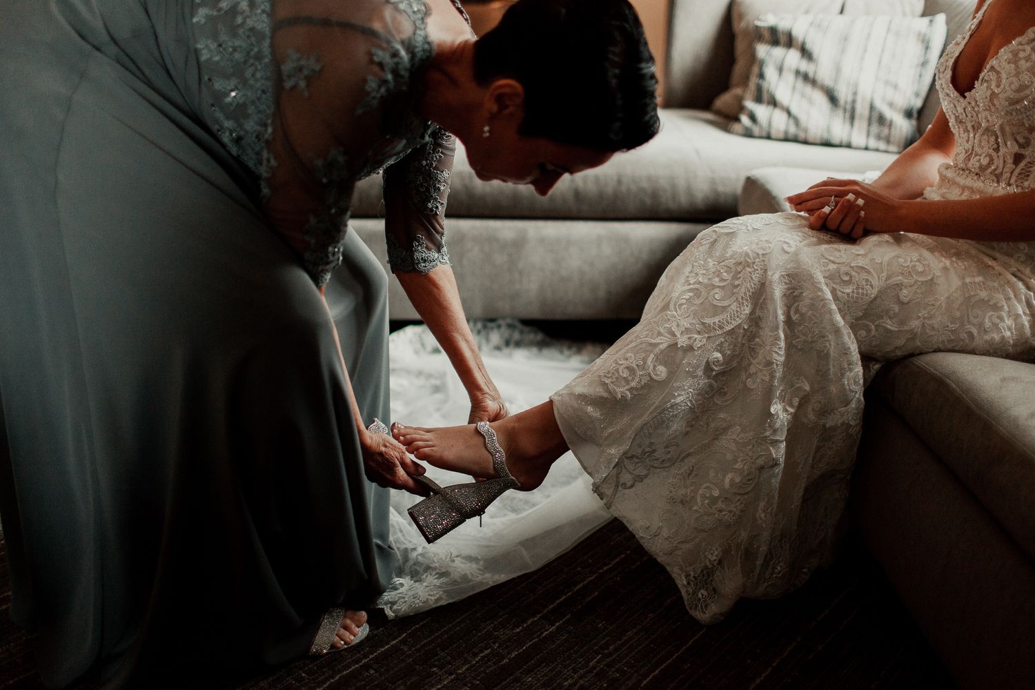 mother of bride helping bride put on her wedding heels