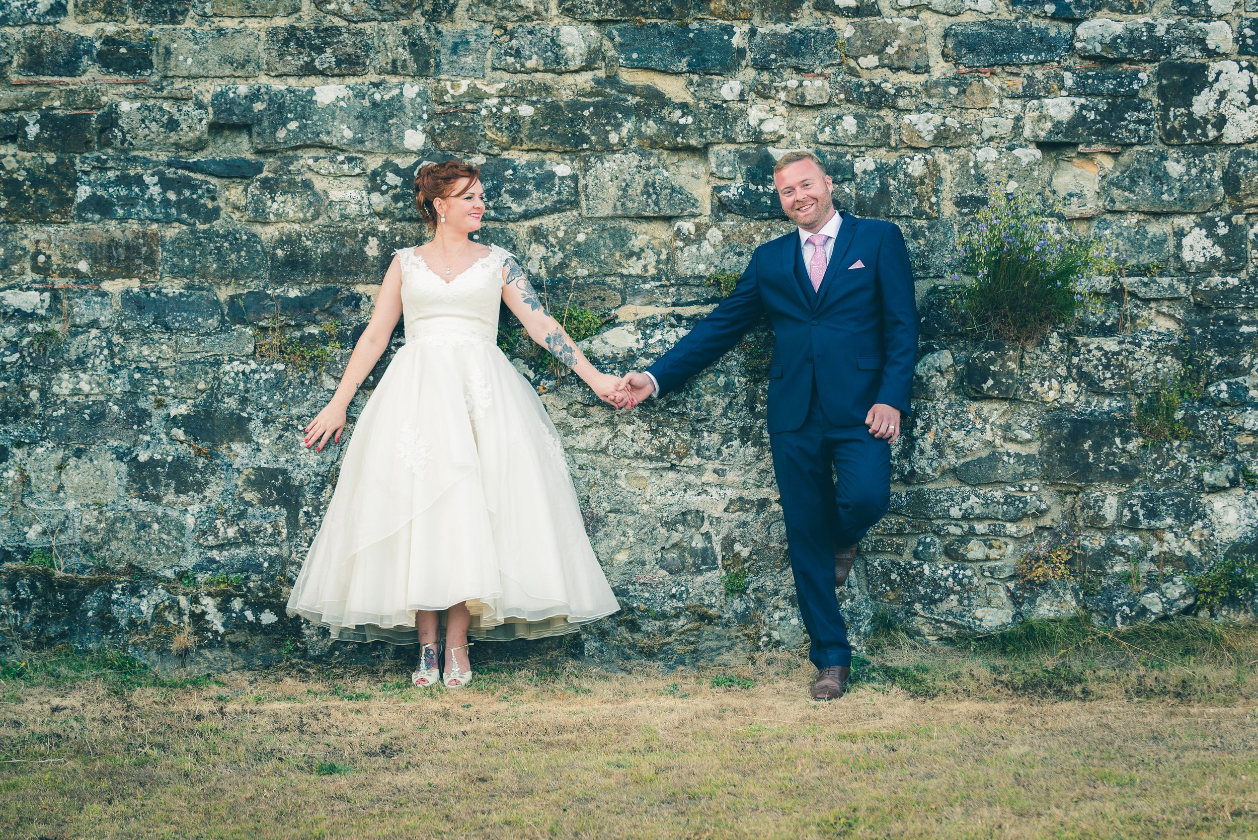 Bride and groom holding hands against a brick wall