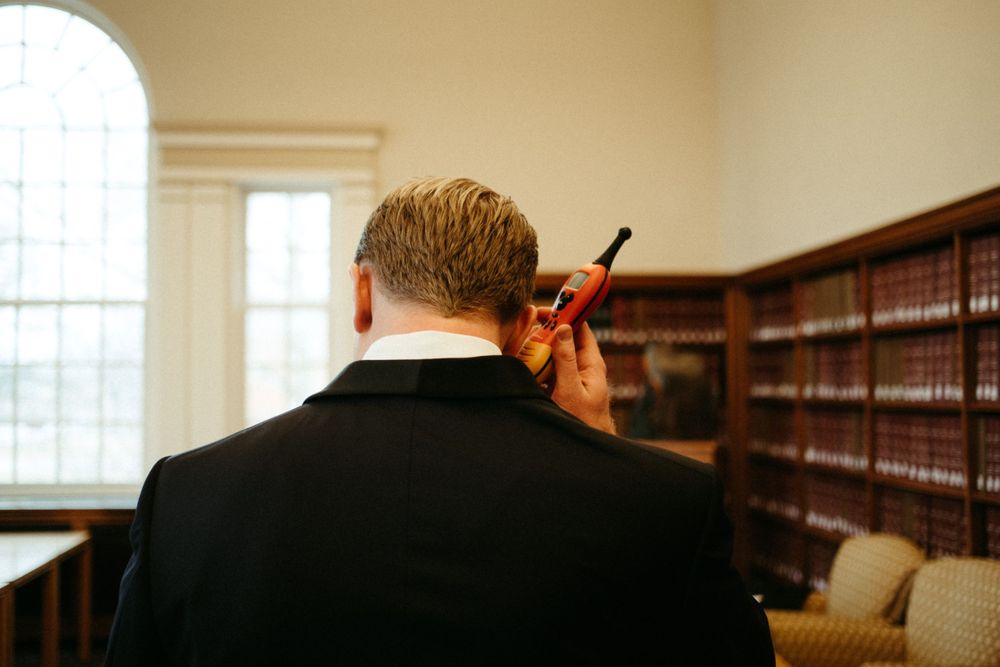 groom-talking-into-walkie-talkies-cowles-library-desmoines-iowa-raelyn-ramey-photography