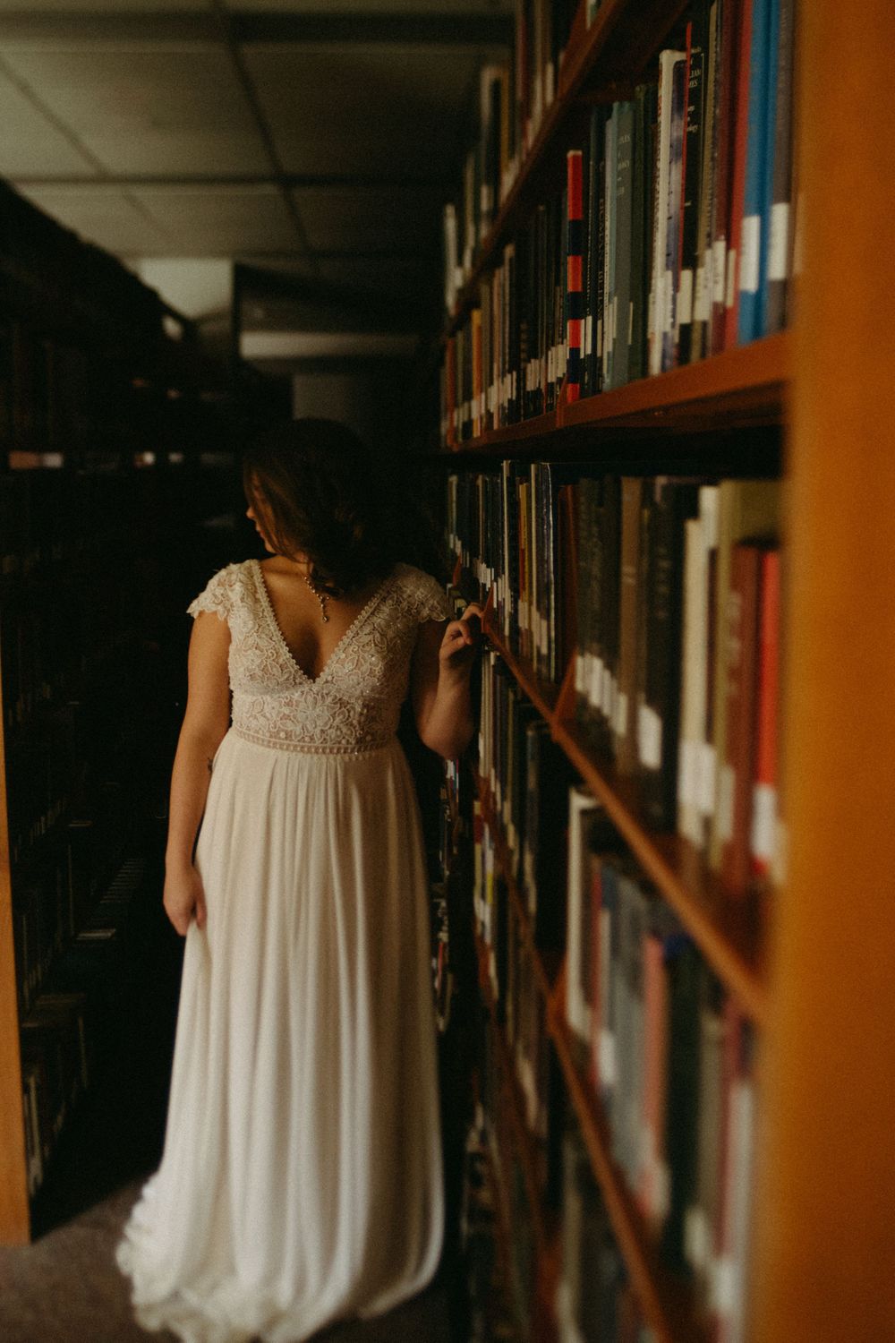 bride-standing-in-book-rows-wedding-cowles-library-desmoines-iowa-raelyn-ramey-photography