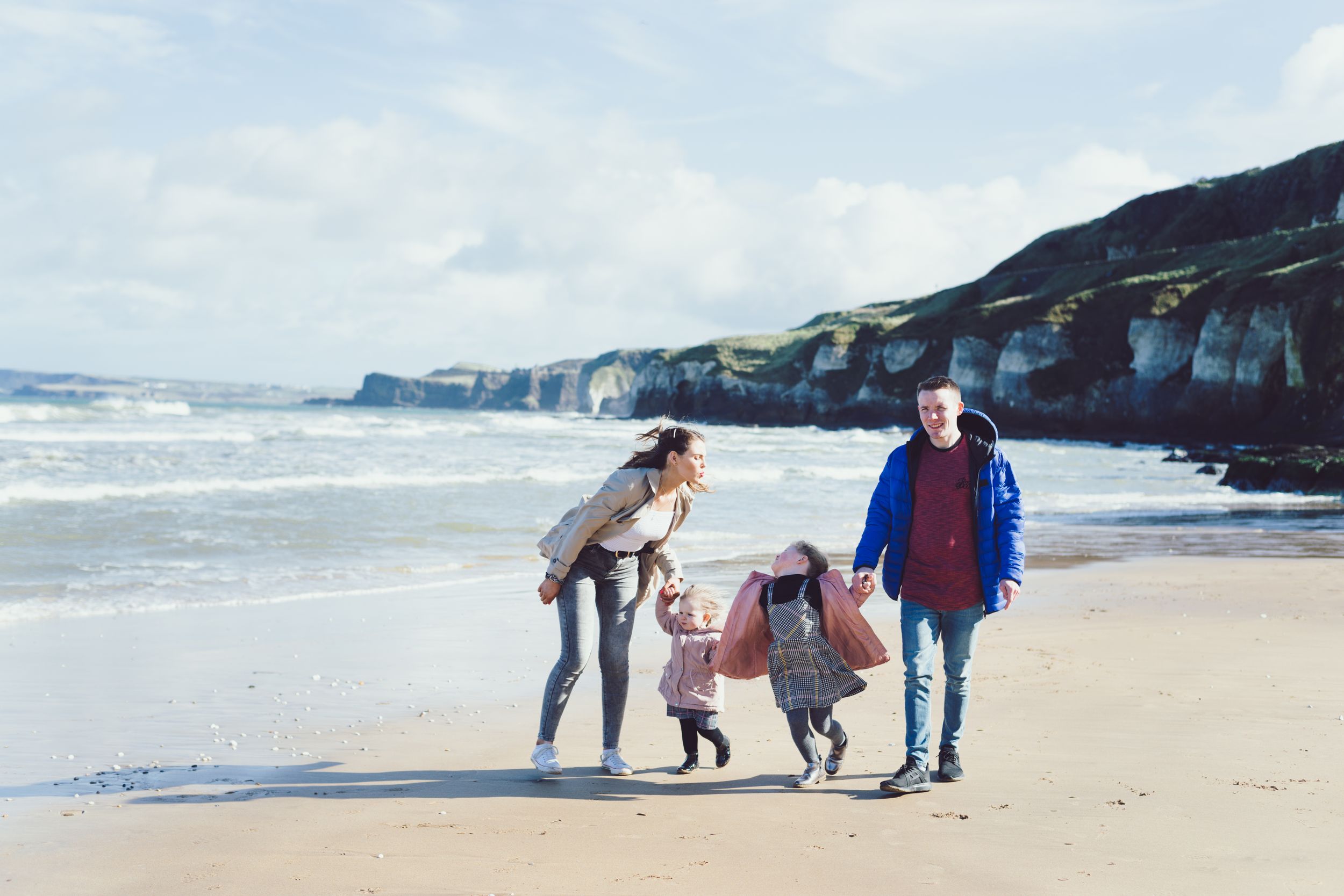 mum, dad and two daughters strolling along the beach at the whiterocks, portrush