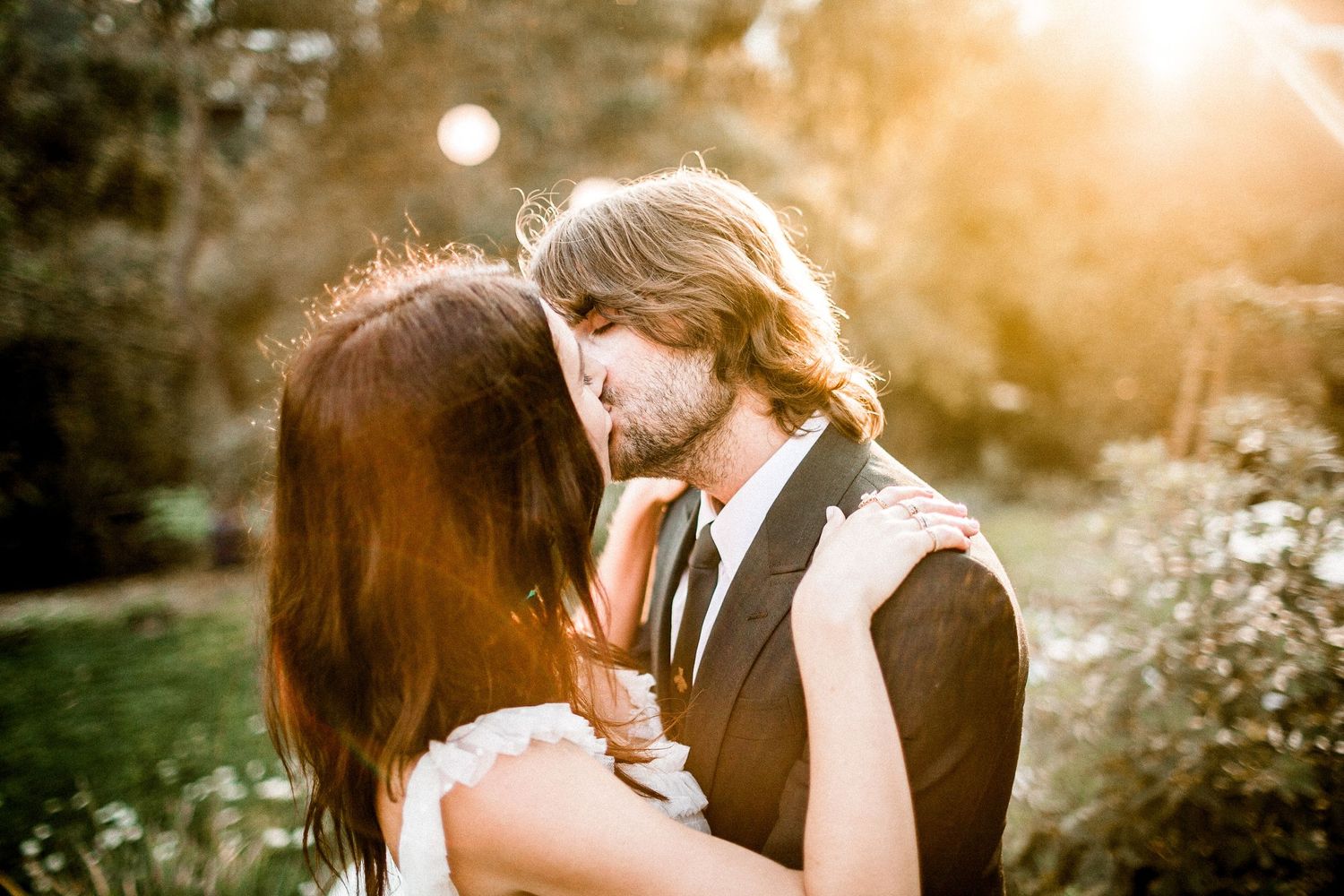 bride kissing groom with golden hour lighting behind