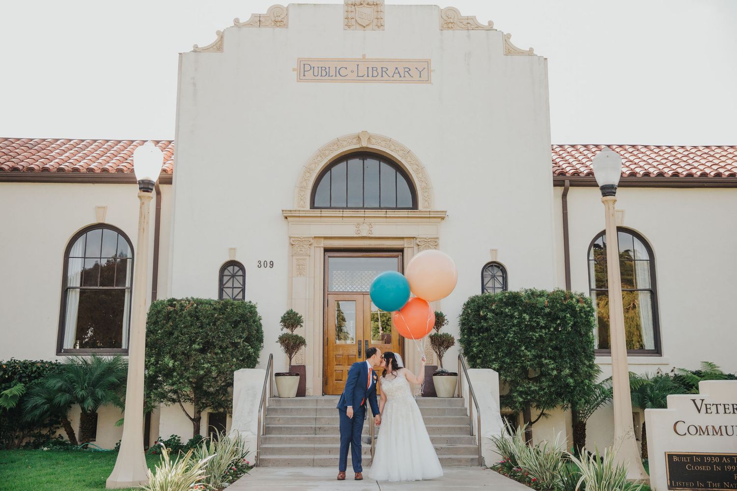 bride & groom with balloons in front of the redondo beach historic library