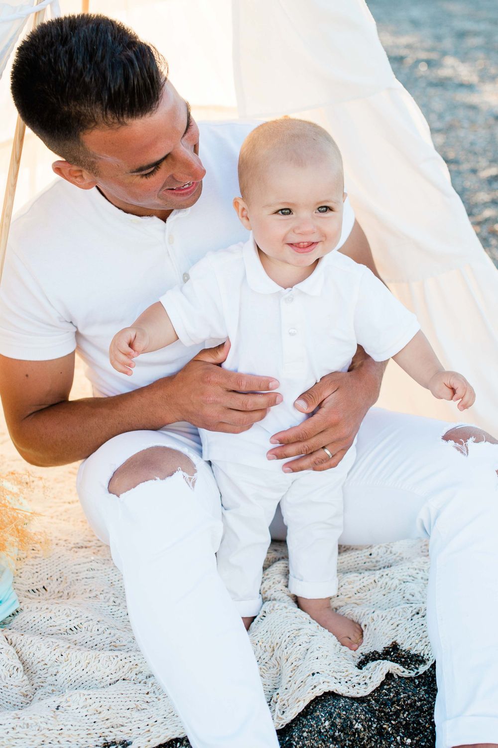 baby boy with his day on the beach laughing