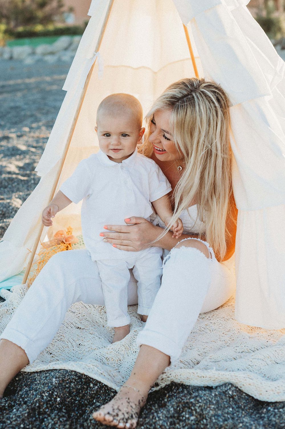Portrait of a mother sitting on the beach holding her baby