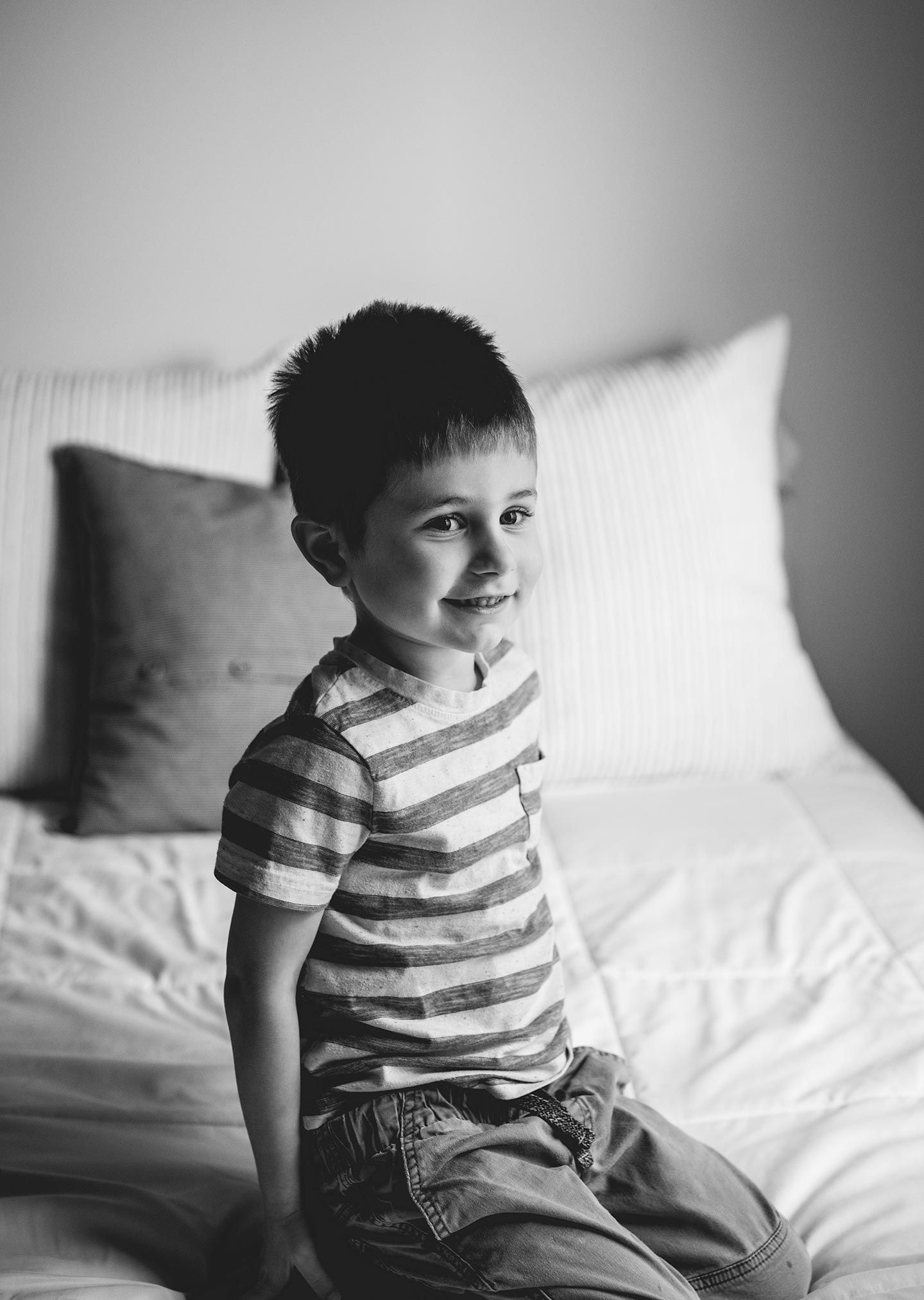 little boy kneeling on bed and smiling
