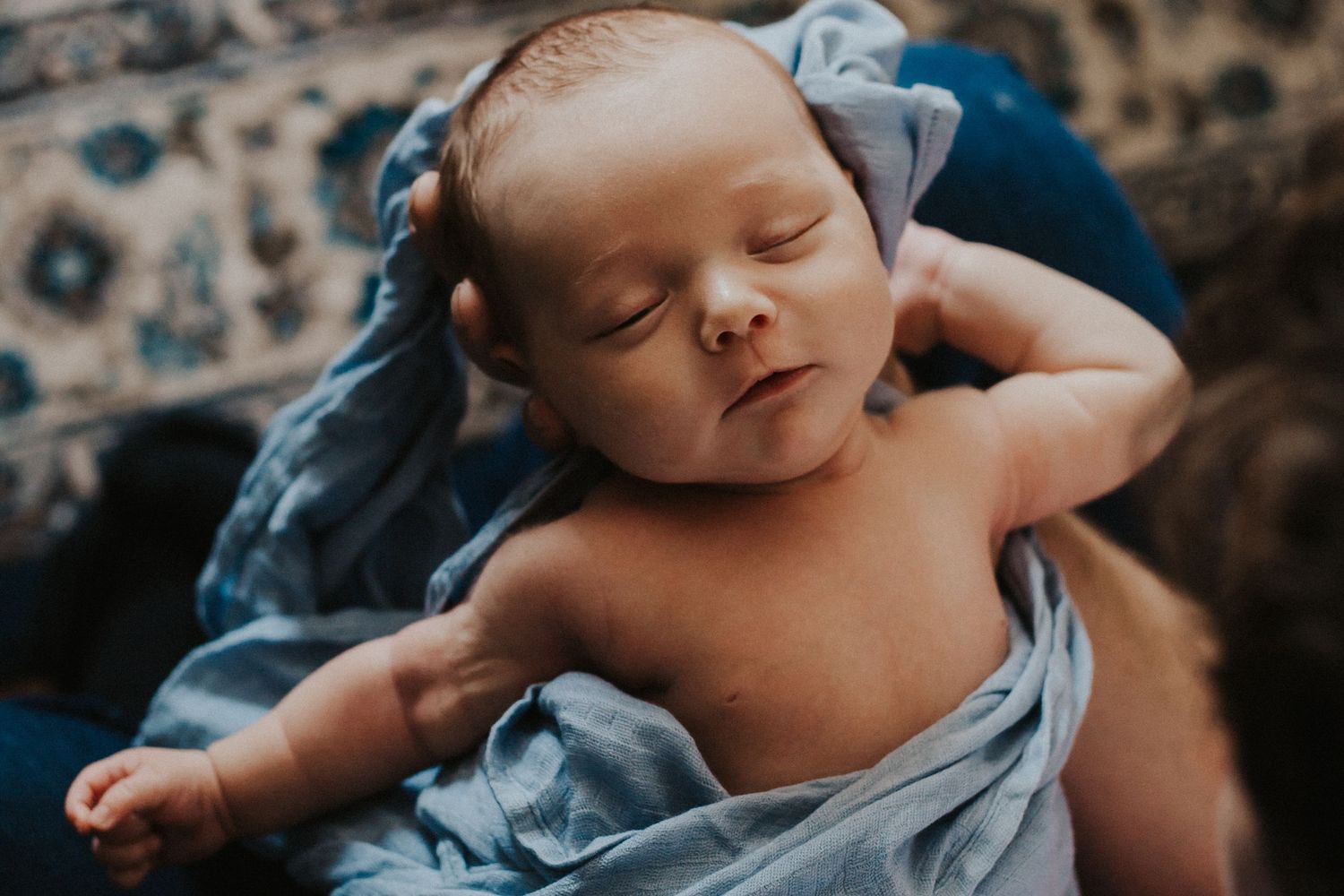 baby boy in blue blanket stretches while sleeping