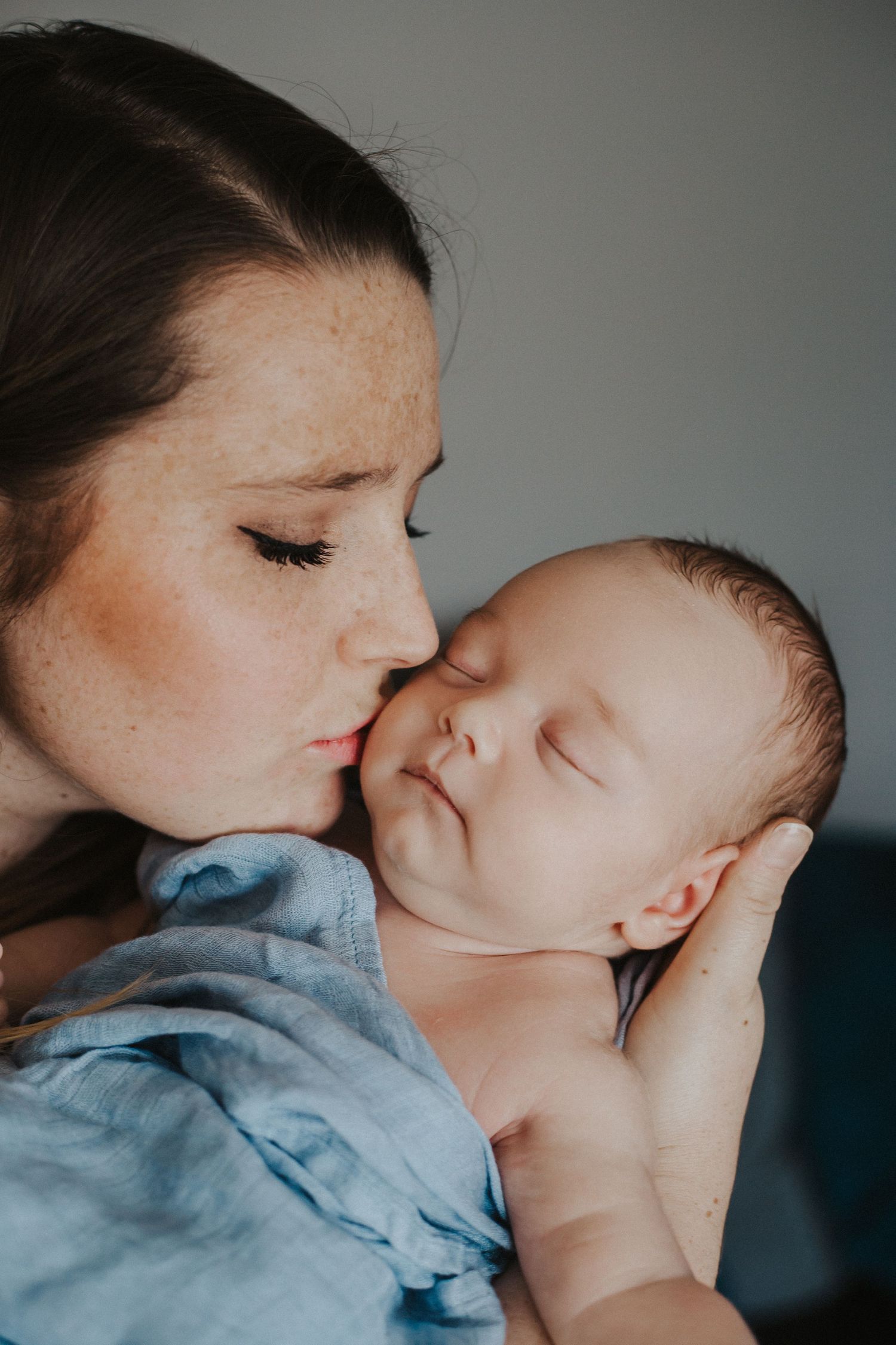 mom kisses baby boy on the cheek while he sleeps
