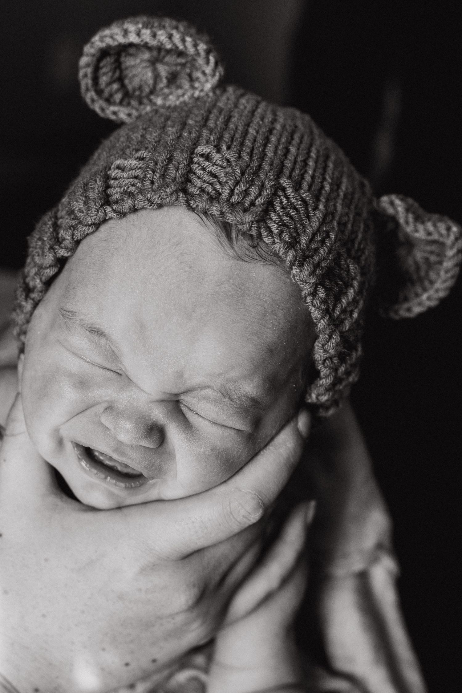 newborn baby boy in bear hat cries