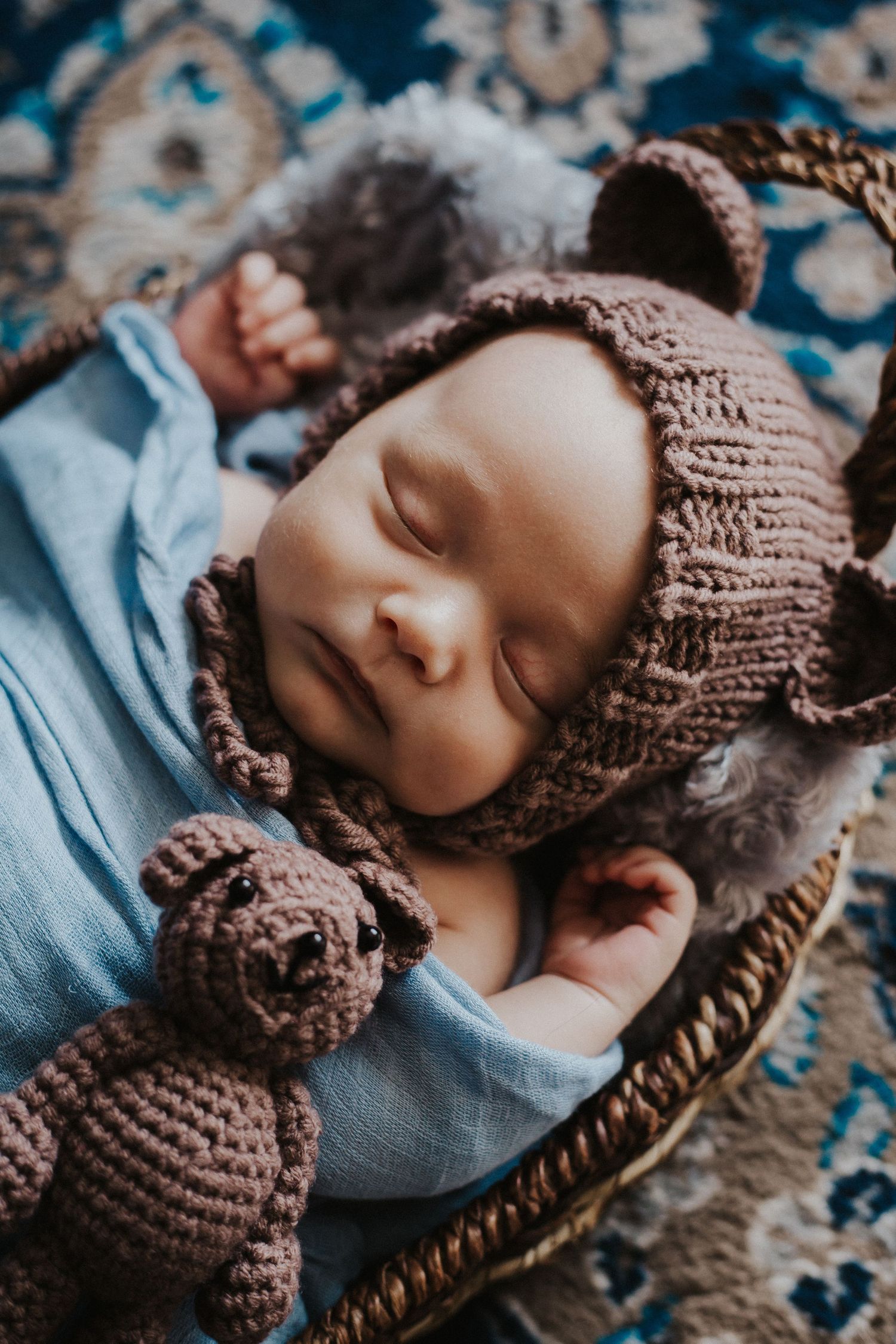 baby boy sleeps in a basket with teddy bear