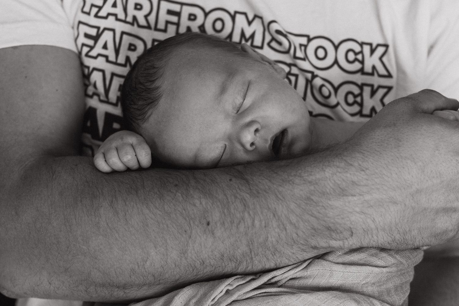 baby boy sleeps on his dad's arm