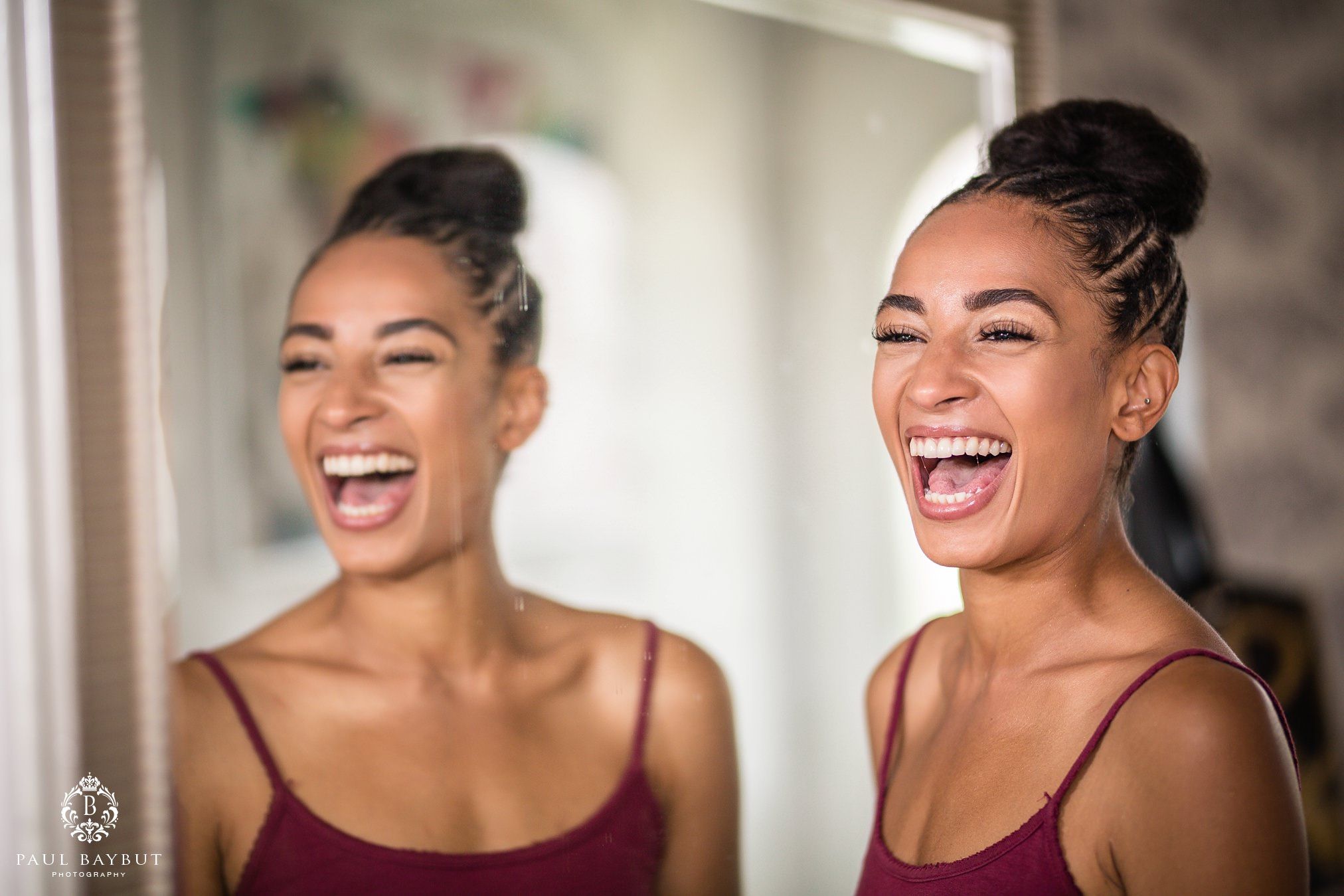 Beautiful bridesmaid laughs with her reflection in a hallway mirror