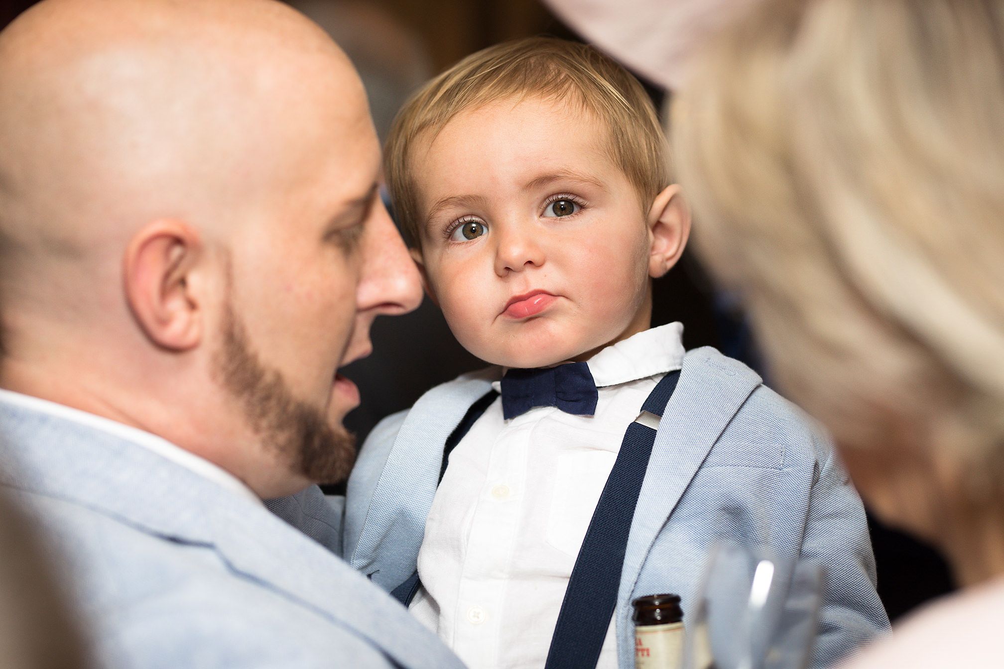 Little boy wedding guest is hugged and adored by his parents