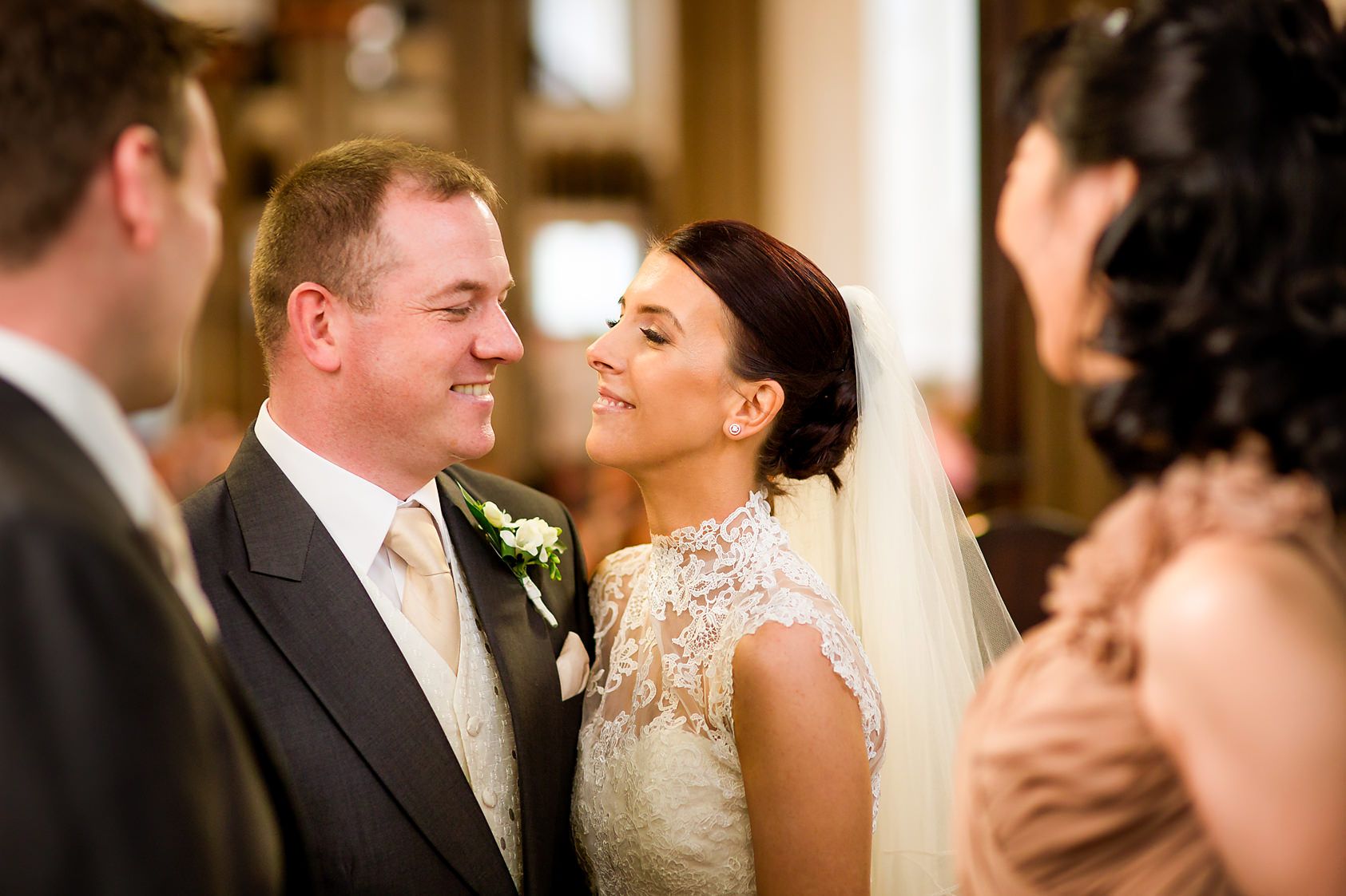 Best man and maid of honour watch the bride and groom as they look at each other in church
