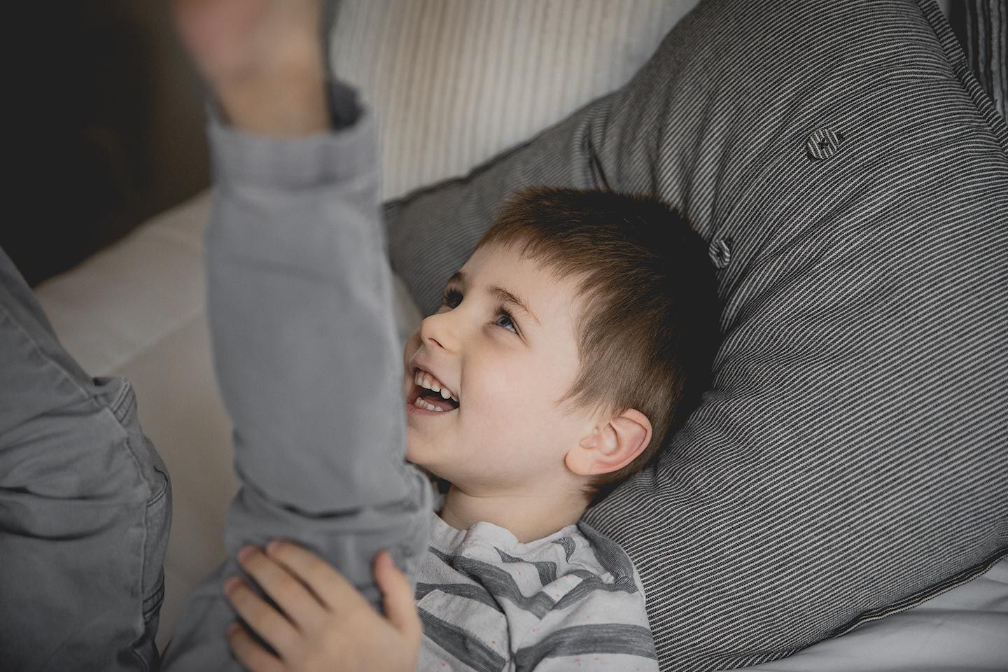 little boy laughing on a bed